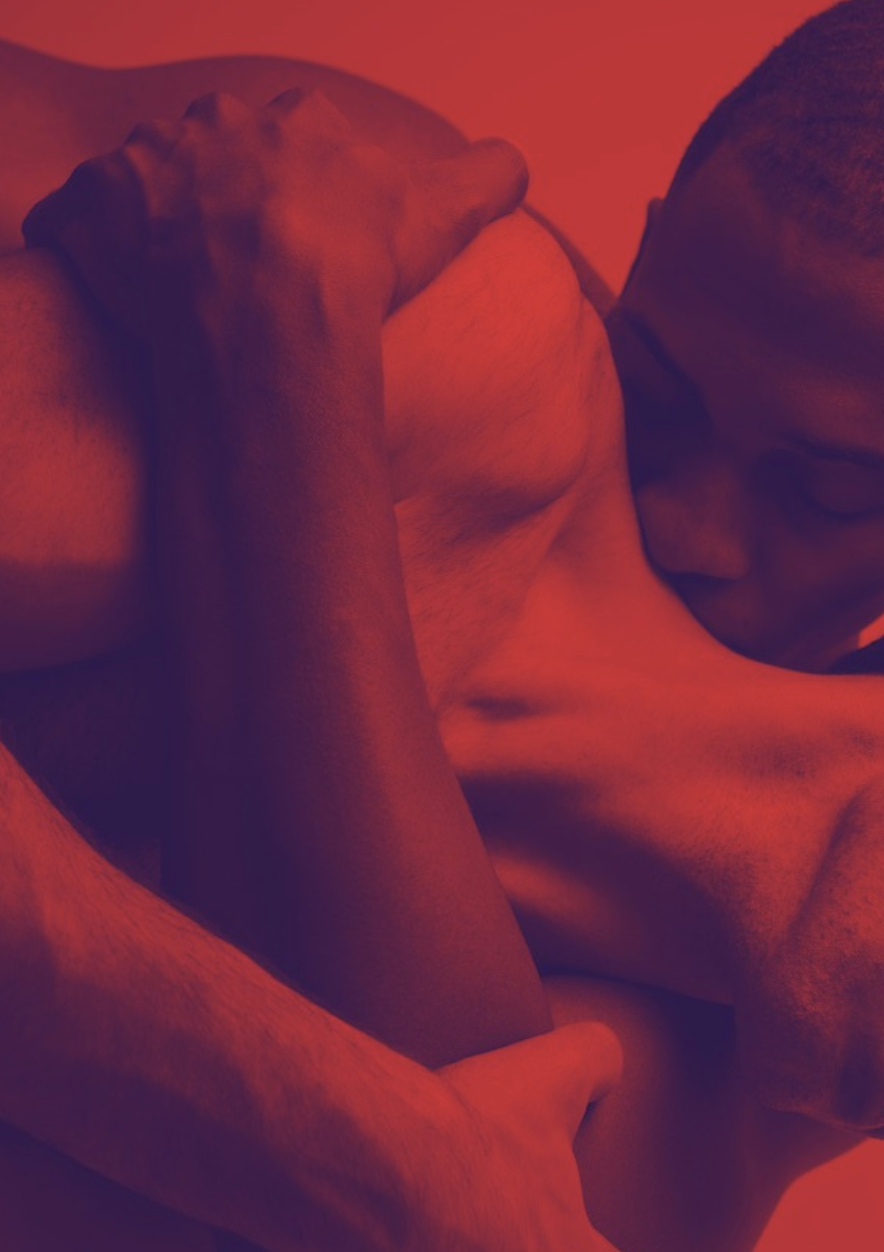 Close-up shot of two men, one Black, one white, in an intimate embrace. Image has red and purple tints.